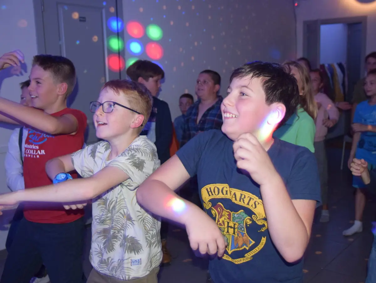 Enfants qui dansent lors d'une fête avec un éclairage disco coloré