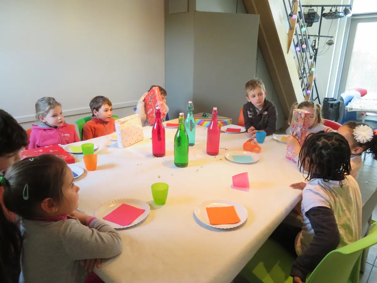 Enfants installés autour de la table de fête d'anniversaire